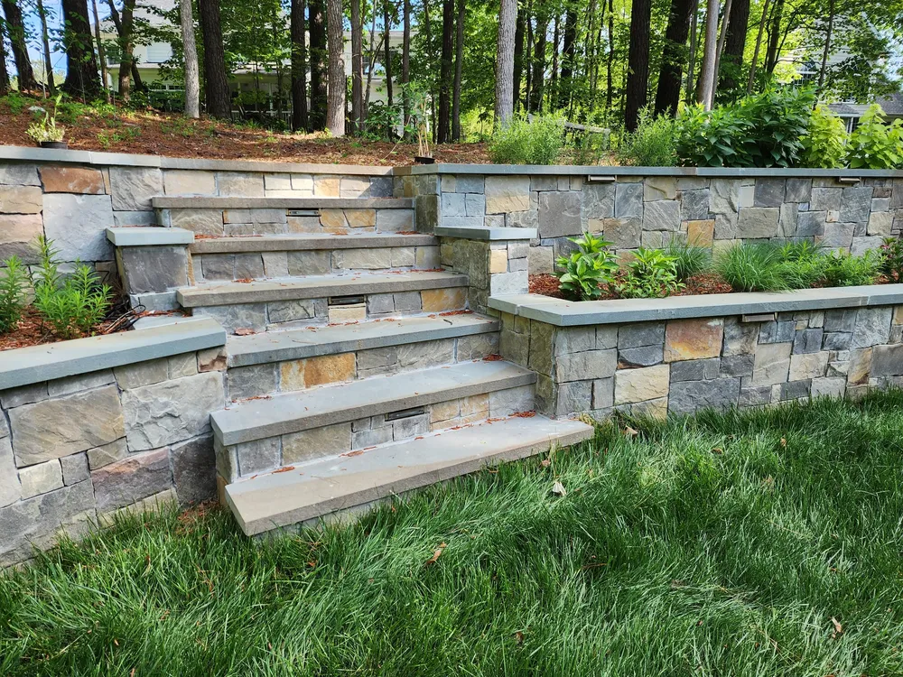 Natural stone steps with bluestone treads and built-in step lights between two tiers of retaining wall