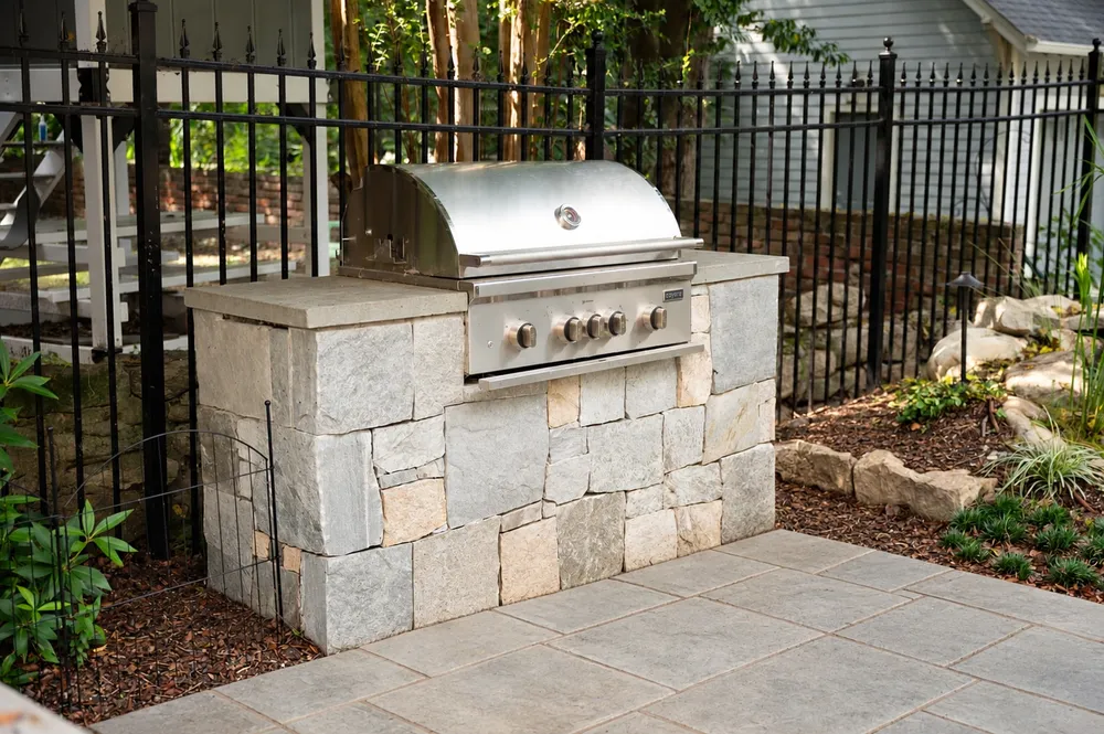 Built-in stainless steel grill set in a natural stone island with a stone countertop