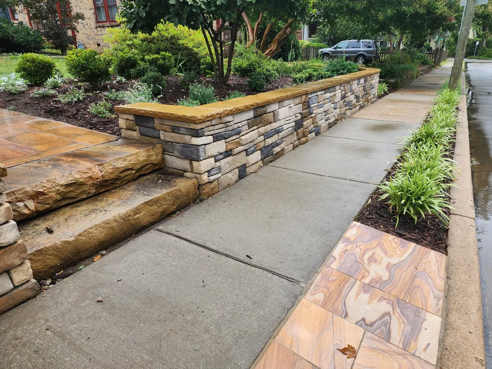 Natural stone slab steps and a rainbow sandstone paver strip alongside the stacked stone wall