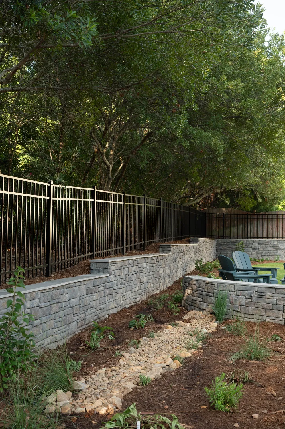 Tiered stone retaining walls with a dry creek bed running through a planted bed