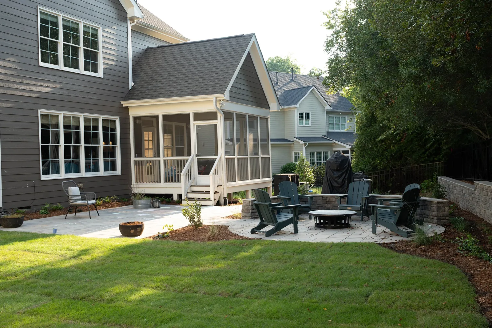 The same backyard after: paver patio, fire pit seating area, new lawn and planting beds