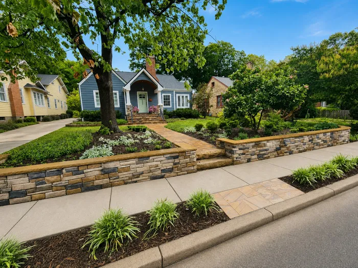 Stacked stone retaining walls and new landscaping in front of a blue bungalow in Raleigh's Five Points neighborhood