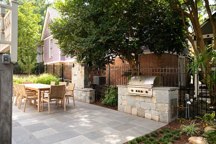Bluestone patio with an outdoor dining area and stone grill island in a Historic Oakwood backyard