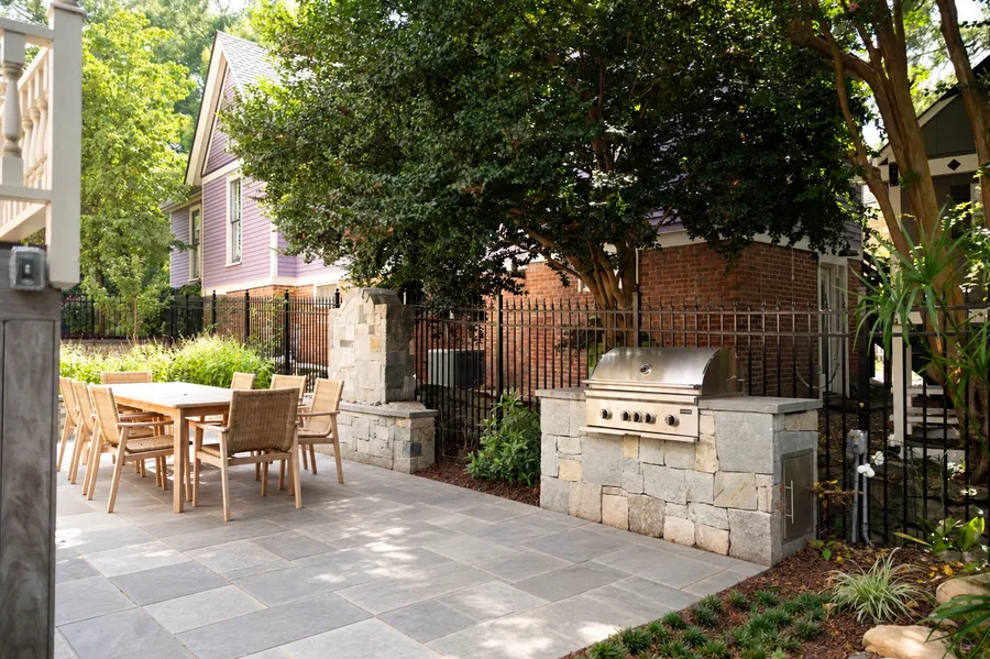 Bluestone patio with an outdoor dining area and stone grill island in a Historic Oakwood backyard