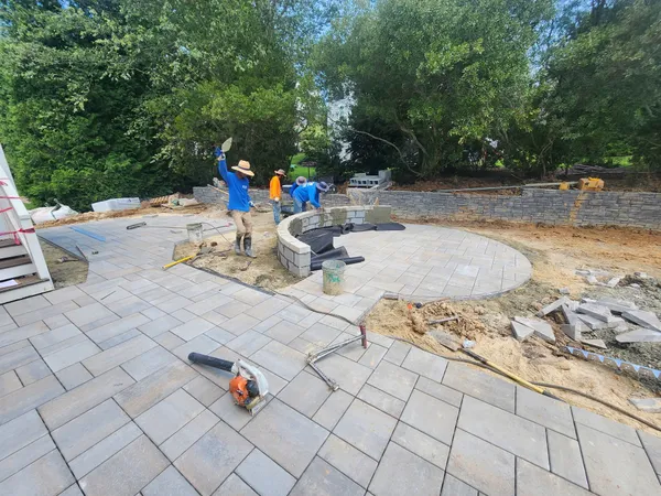 The Carved Earth crew building a curved stone seat wall on a new paver patio